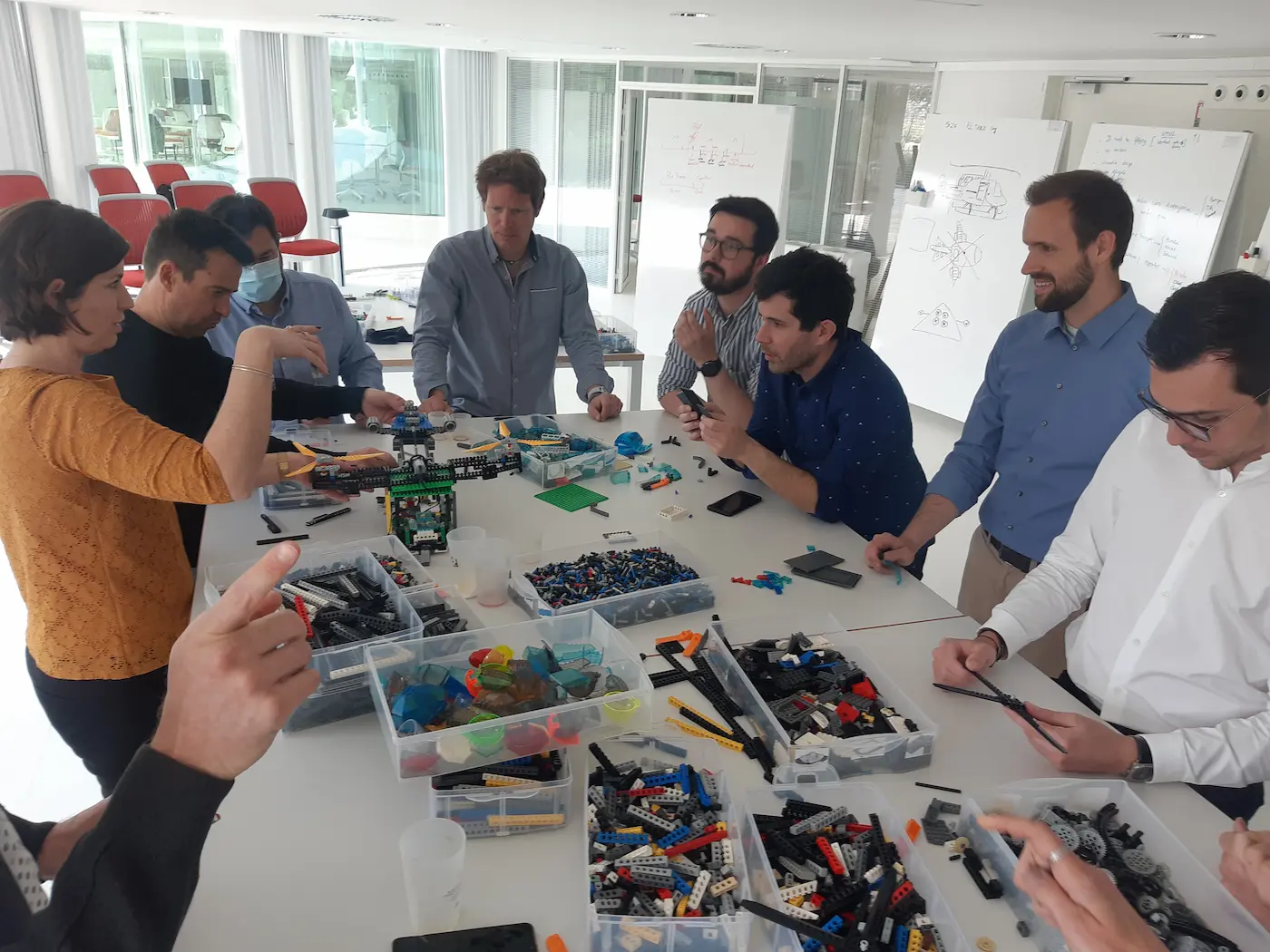 Hub entreprises 1 20/10/2026 Animation entreprise : des collaborateurs construisent ensemble en briques LEGO® autour d'une table couverte de bacs de pièces, devant des tableaux blancs