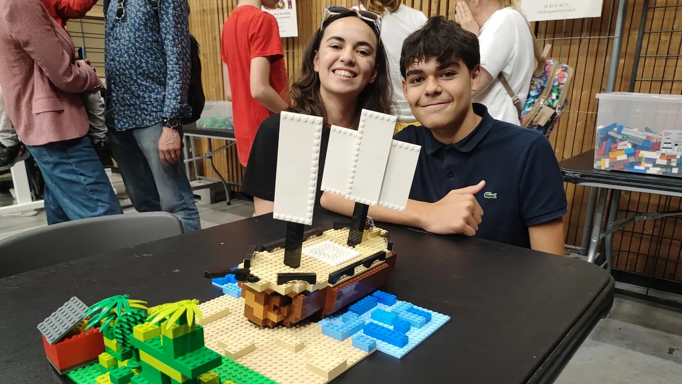 Sous-Hub Événement entreprise 7 20/10/2026 Animation de salon : deux visiteurs lèvent le pouce devant un bateau pirate construit en briques LEGO® sur une table