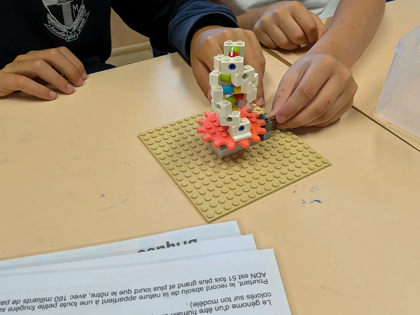Sous-Hub écoles 3 21/10/2026 Animation école, atelier pédagogique STEAM : un élève assemble un mécanisme à engrenages en briques LEGO® avec sa notice de montage