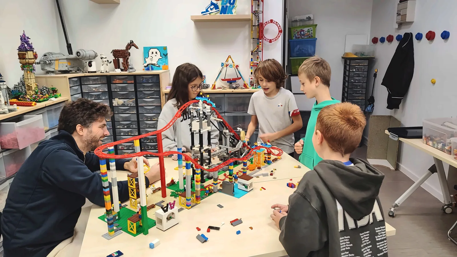 Activités extrascolaires à Salon-de-Provence : Johann, co-fondateur de Ludi Briques, et quatre membres du club autour d'une montagne russe en briques LEGO®