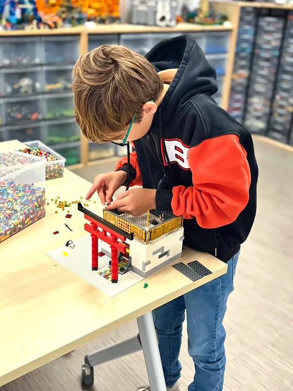 Un membre du club concentré sur la construction d'un portail japonais en briques LEGO®