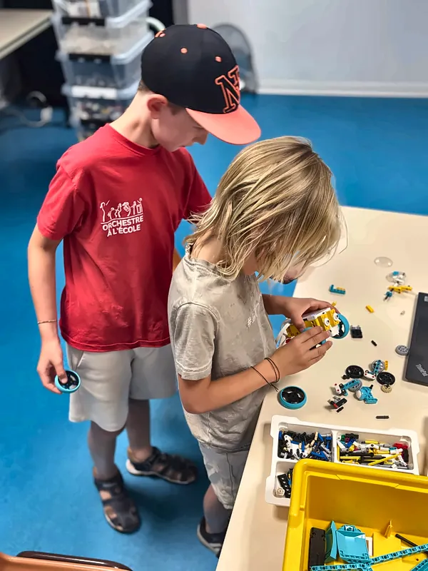 Deux membres du club robotique assemblent les roues d'un robot SPIKE™ Prime au centre de Salon-de-Provence