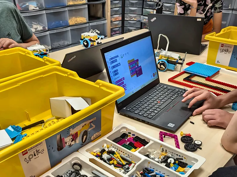 Écran d'ordinateur affichant un programme Scratch en blocs, à côté d'un robot SPIKE™ Prime, au club robotique de Salon-de-Provence