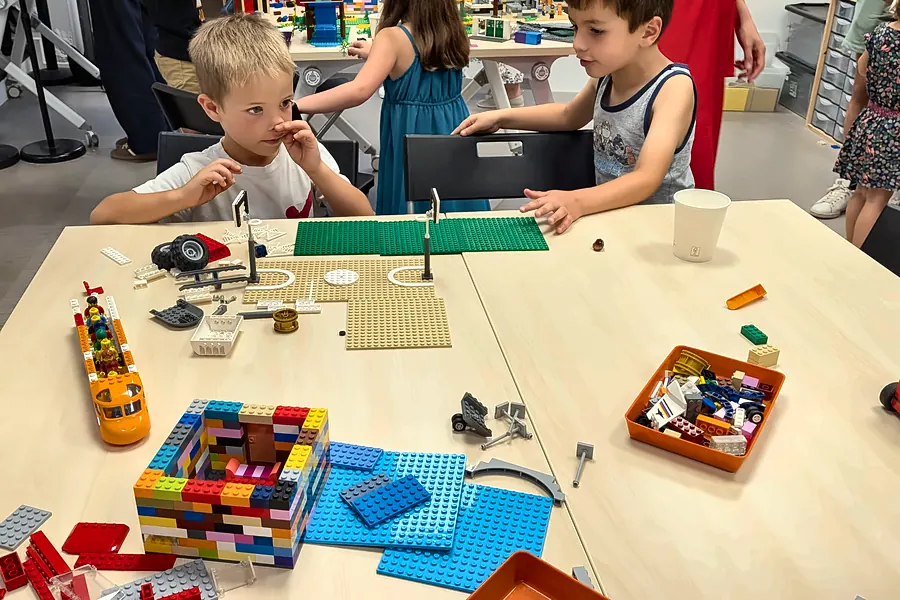 Enfants qui construisent en accès libre dans la salle de jeux de Salon-de-Provence : plaques vertes, bacs de pièces et créations en briques LEGO® sur la table