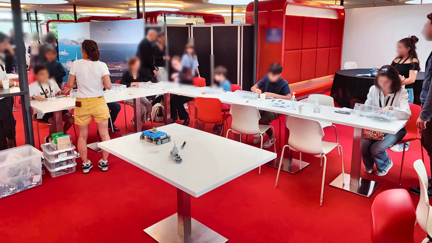 family day entreprise 5 21/10/2026 Family day entreprise pour Naval Group à Paris : familles et enfants construisent en briques LEGO® autour de tables blanches, dans une salle de réception rouge