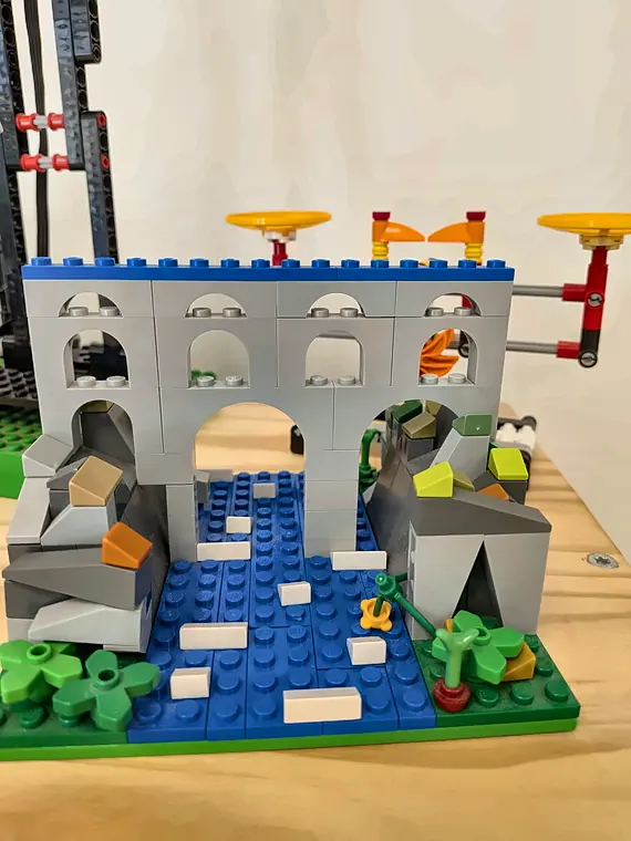Accès libre 10 20/10/2026 Aqueduc gris en briques LEGO® au-dessus d'une rivière, avec rochers, hélices jaunes et petite cascade