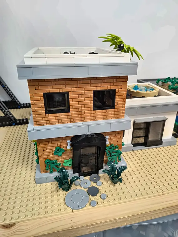 Accès libre 8 20/10/2026 Maison moderne à deux étages en briques LEGO® orange et blanches, avec toit-terrasse et plantes, construite en accès libre