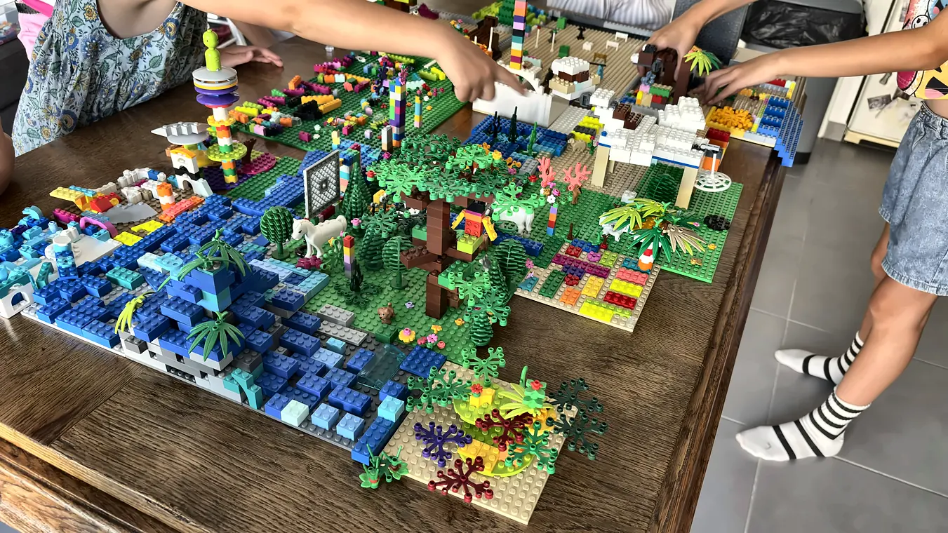 Grand diorama en briques LEGO® avec forêt, océan bleu et récif, construit en équipe par des enfants pendant un anniversaire