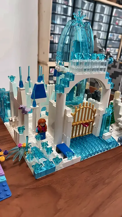 Stage vacances 17 20/10/2026 Palais de glace de La Reine des neiges®, de Disney®, en briques LEGO® blanches et transparentes, avec une grille dorée et une minifigurine à l'entrée