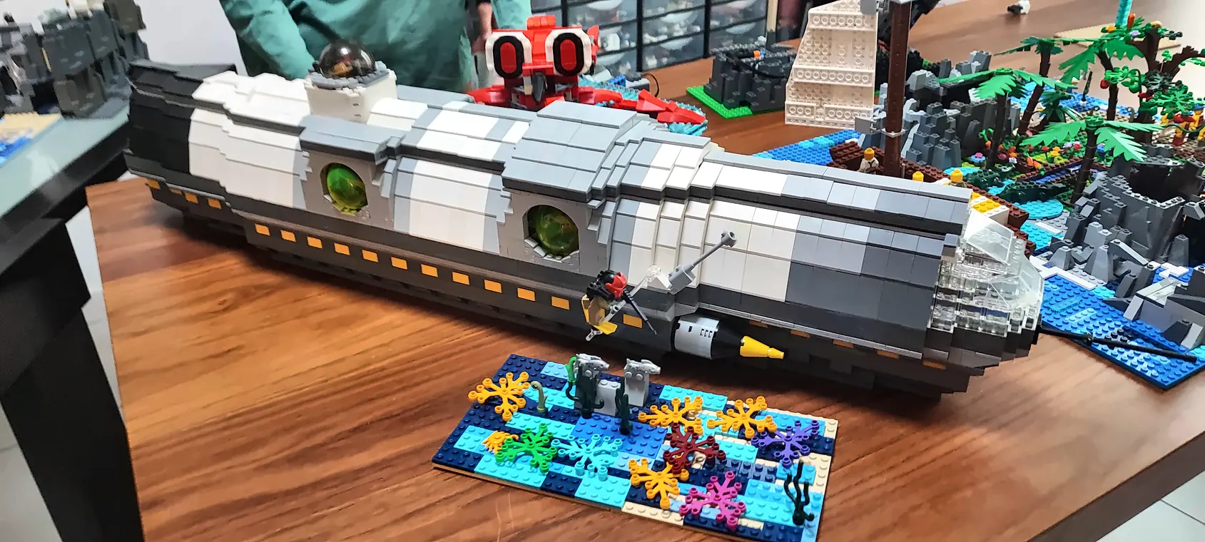 Stage vacances 18 20/10/2026 Sous-marin géant Nautilus, de Vingt mille lieues sous les mers de Jules Verne, en briques LEGO® avec ses hublots verts, posé près d'un fond marin en briques