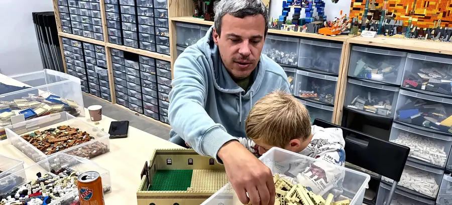 Un adulte et un enfant choisissent des briques LEGO® dans un bac, à l'accès libre du centre de Salon-de-Provence