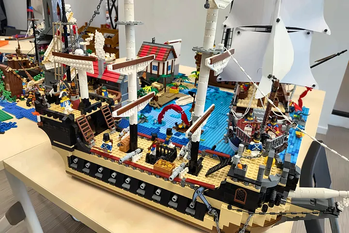Vaisseau de ligne pirate en briques LEGO® avec ses canons, ses voiles blanches et une petite île, construit pendant un stage vacances scolaires à Salon-de-Provence